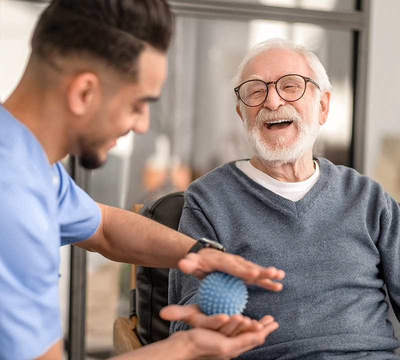 A caretaker helping an elderly man with therapy