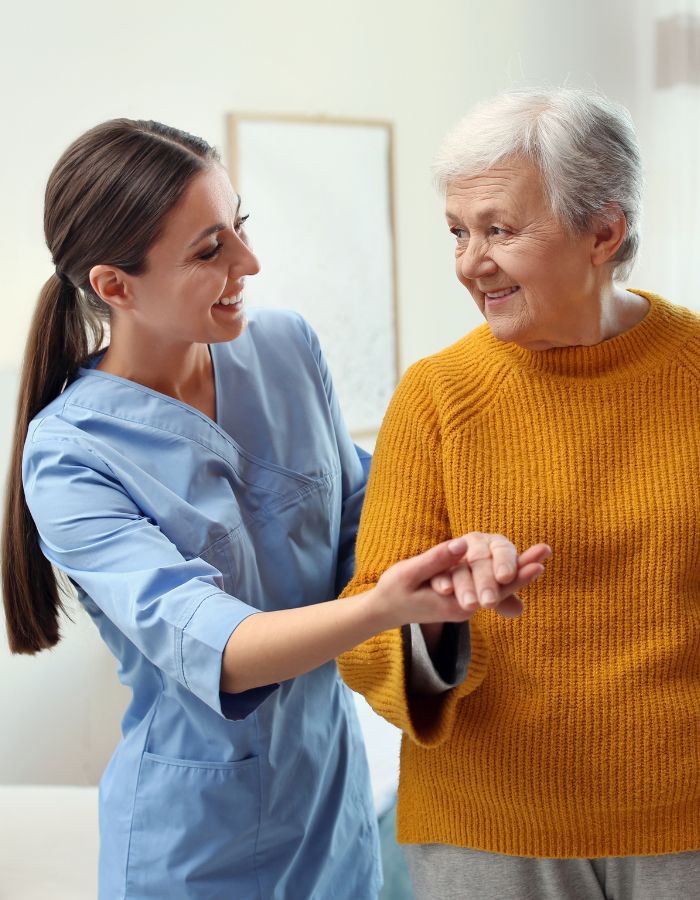 Elderly woman with a caretaker. The Caretaker is helping steady the elderly woman.