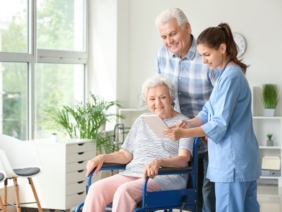 A couple with a caretaker looking at a tablet device together